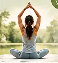 Woman practicing yoga in a seated meditation pose outdoors beside a peaceful lake surrounded by nature.