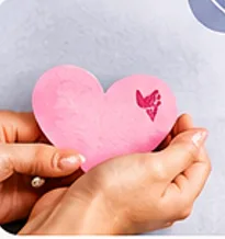 Hands gently holding a pink heart symbolizing self-love, emotional wellness, and compassion.